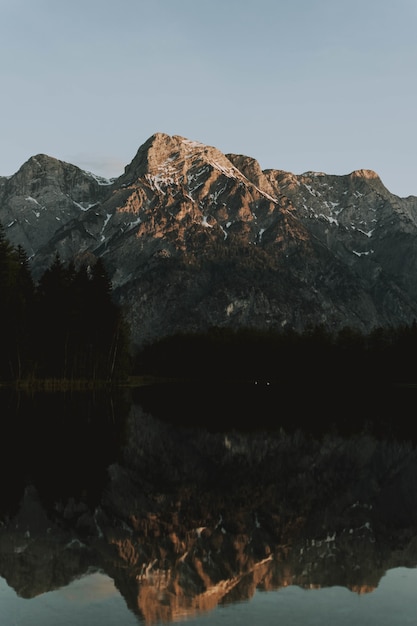 Lago cercado por montanhas com árvores refletindo na água durante o dia