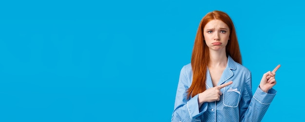 Lamentar o mau humor e o conceito de publicidade triste menina ruiva infeliz em roupas de dormir emburrada e carrancuda e