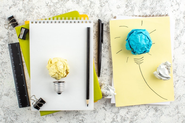 Lâmpada de papel em caderno espiral fechado branco e material de escritório em superfície branca