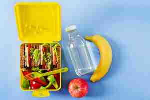 Foto grátis lancheira escolar saudável com sanduíche de carne e legumes frescos, garrafa de água e frutas