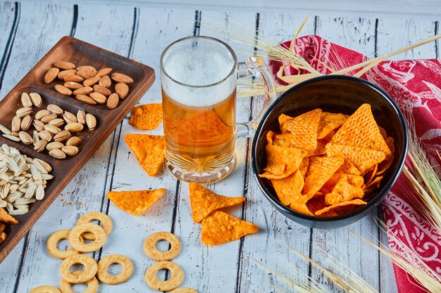 Lanches variados, batatas fritas e um copo de cerveja na mesa azul.