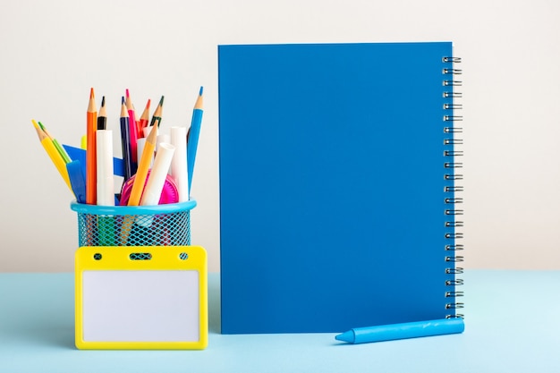 Foto grátis lápis coloridos diferentes de vista frontal com caderno azul na mesa azul