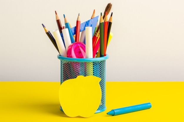 Lápis coloridos diferentes de vista frontal com canetas hidrográficas na mesa amarela