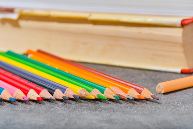 Lápis de cor e livros antigos em uma mesa cinza claro closeup foco seletivo fundo desfocado De volta ao modelo de layout de conceito de educação escolar