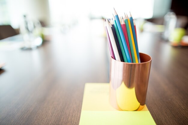 Lápis de cor em copo na mesa de conferência