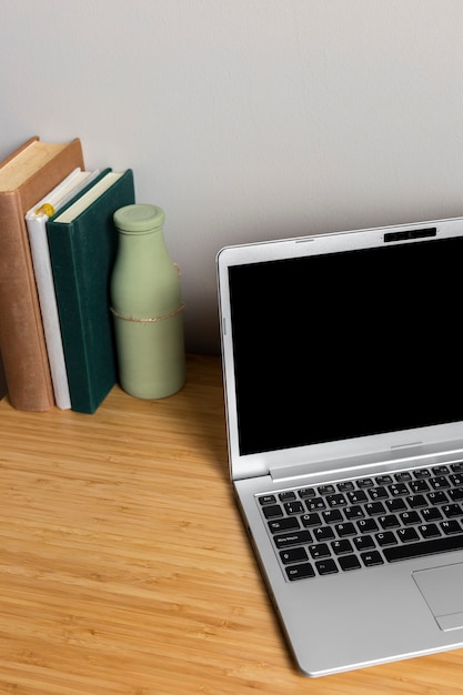 Foto grátis laptop cinza com livros na mesa de madeira