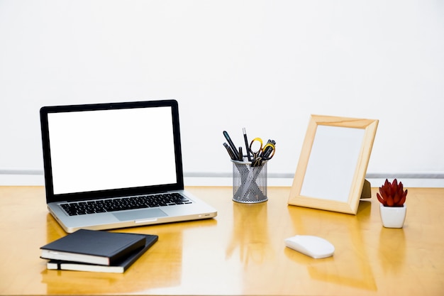 Laptop com moldura em branco na mesa de madeira