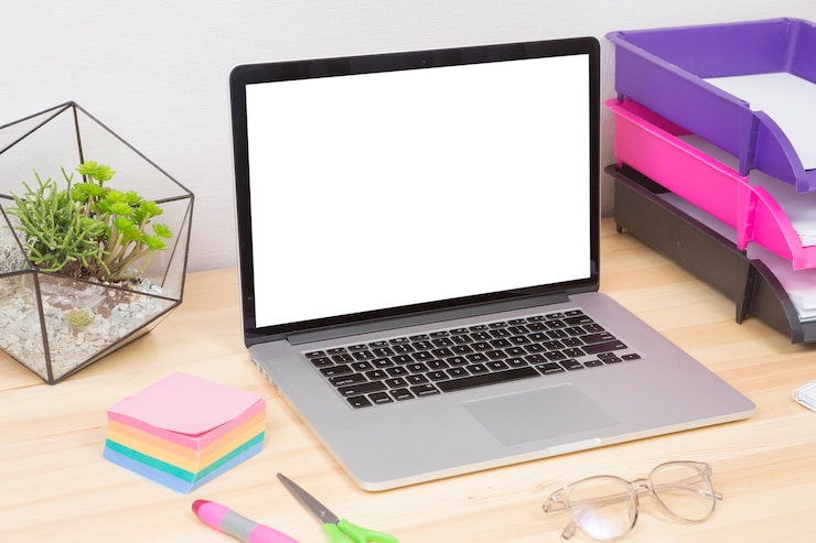 Foto grátis laptop com planta verde e adesivos na mesa