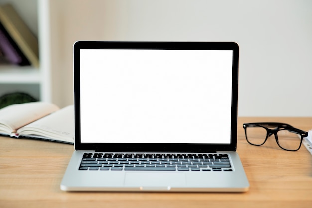 Laptop com tela em branco na mesa de madeira