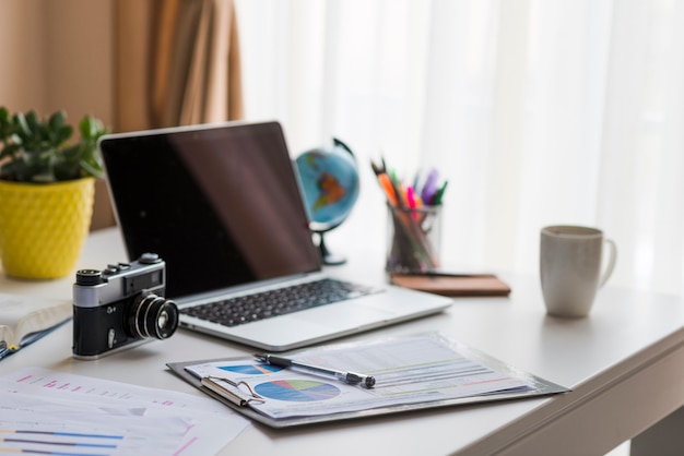 Laptop e câmera na mesa do escritório