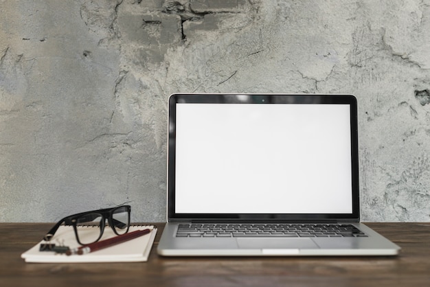 Laptop e espetáculo com papelaria de escritório na mesa de madeira com parede velha