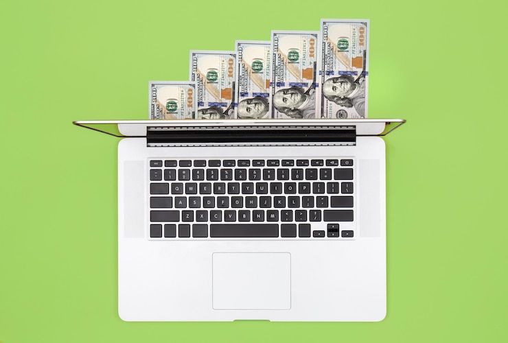 Foto grátis laptop e notas de dólar na configuração plana de fundo colorido