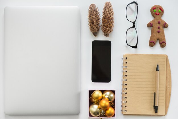 Laptop fechado, telefone celular, material de escritório e decoração de Natal