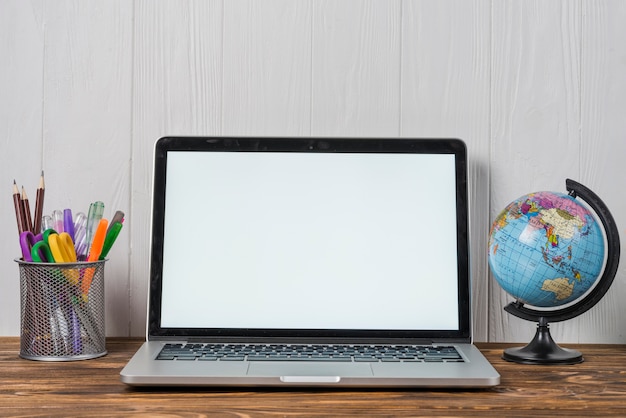 Laptop perto de globo e papelaria