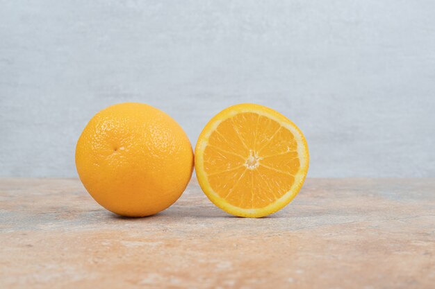 Laranja suculenta e meia laranja cortada na mesa de mármore.