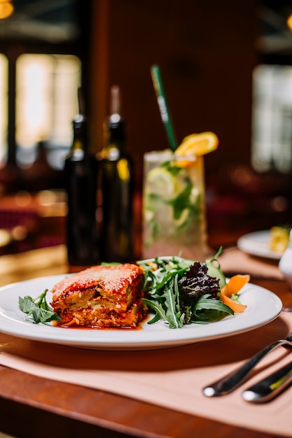 Lasanha italiana servida com salada de rúcula