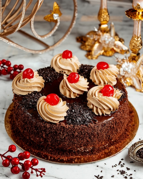 Lateral do bolo de chocolate com chantilly e cerejas em cima da mesa