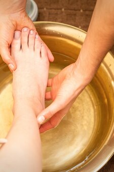 Lavar os pés femininos em um recipiente especial por massagista em salão de spa.