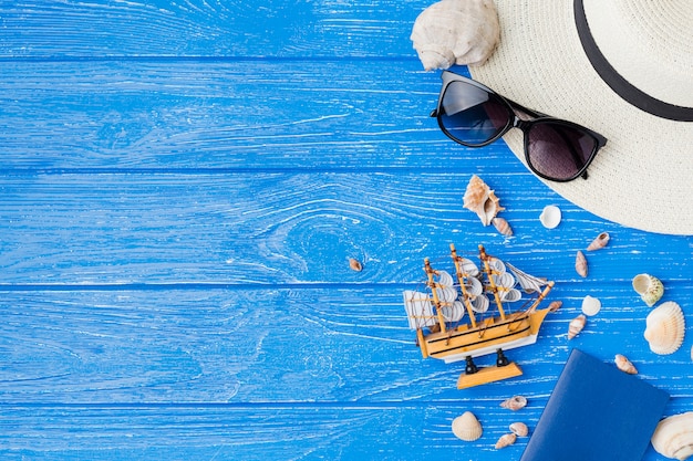 Layout de conchas do mar perto de navio de brinquedo e óculos de sol com chapéu