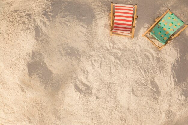 Layout de pequenas espreguiçadeiras decoradas na areia