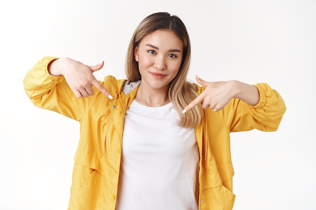 Legal atrevida, bonita, hippie asiática, loira, menina, assertiva, levantar, dedos indicadores apontando para baixo sorrindo afetadamente determinadas emoções positivas autoconfiantes dizendo a melhor escolha propor olhar para baixo