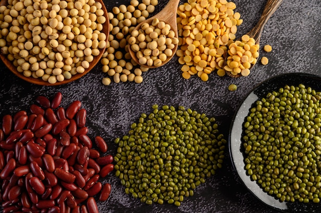 Legumes e variedade de feijões no chão de cimento preto.