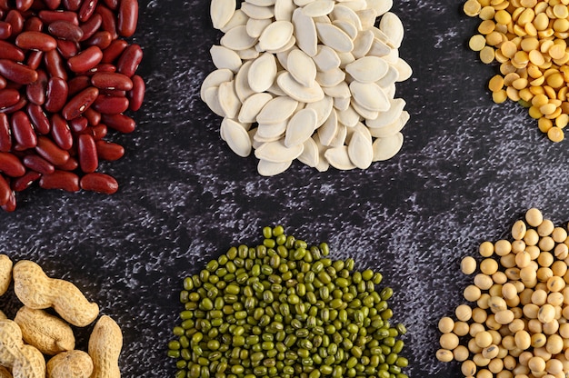 Legumes e variedade de feijões no chão de cimento preto.