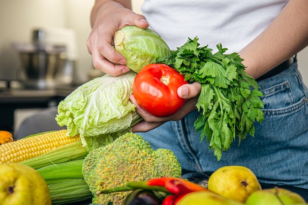 Legumes em mãos femininas o conceito de preparação de alimentos na cozinha