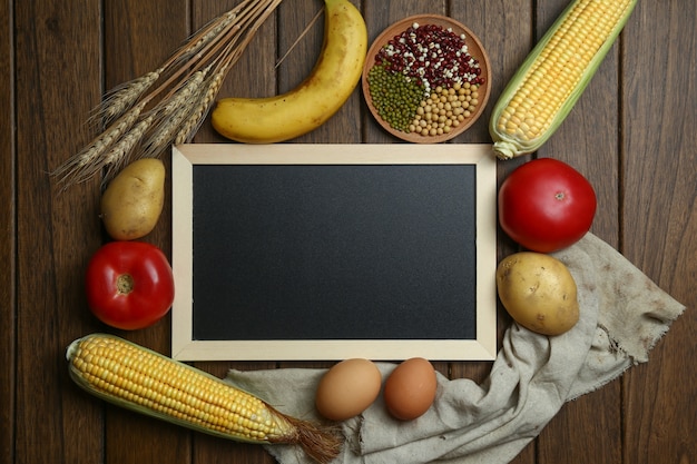 Legumes orgânicos frescos, frutas, ovos, feijões e grãos com quadro-negro na mesa de madeira vintage