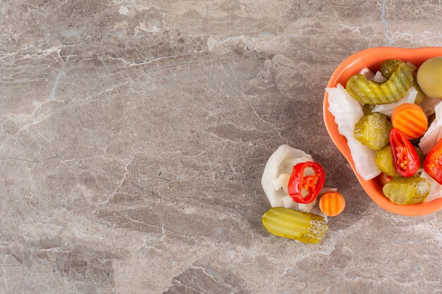 Legumes variados em pickles em uma tigela colocada na mesa de pedra.