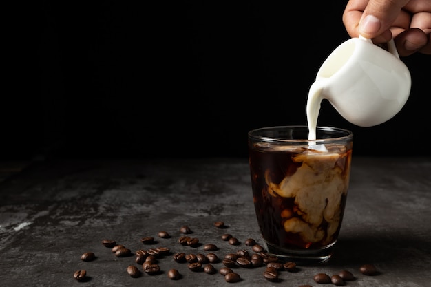 Leite, derramando em café preto gelado na mesa