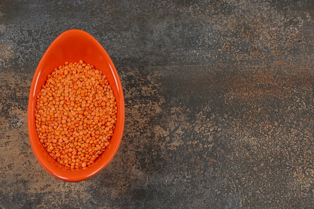 Foto grátis lentilhas vermelhas secas em uma tigela laranja.