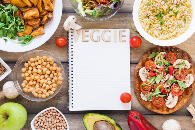 Letras de legumes no notebook cercado por comida vegetariana
