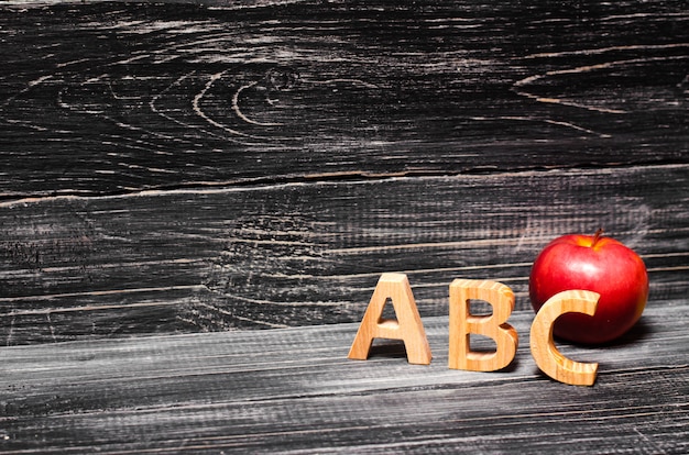 Letras do alfabeto e maçã vermelha em um fundo preto Foto Premium