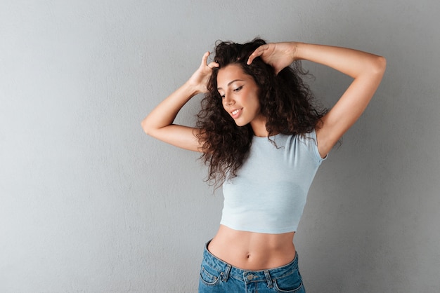 Levantamento feliz da mulher isolado sobre o cinza