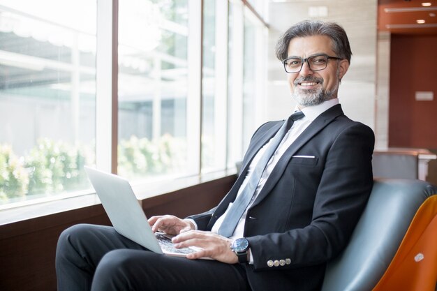 Líder de negócios feliz usando Tablet no lobby