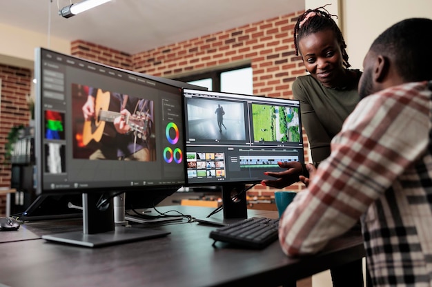 Líder do departamento de pós-produção aconselhando o colega a melhorar as cores e a qualidade dos quadros das imagens. Editores de vídeo profissionais criativos colaborando para terminar o projeto do filme dentro do prazo.