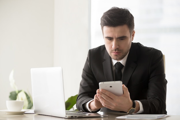 Líder empresarial masculino navegando recursos on-line usando gadgets