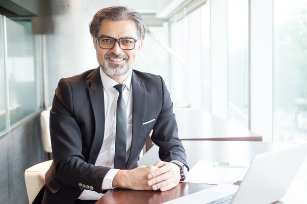 Líder empresarial sorridente sentado na mesa de escritório