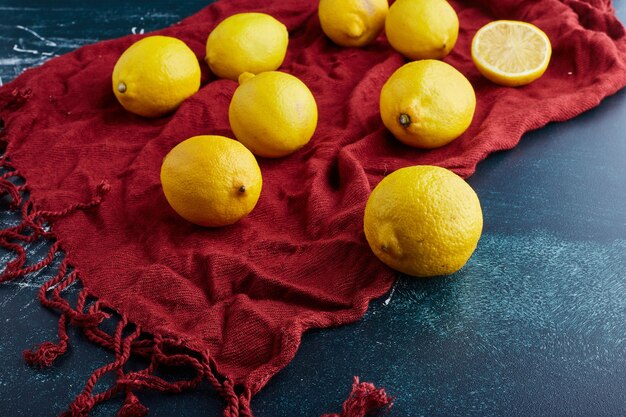 Limão amarelo e fatias sobre fundo azul em uma toalha vermelha.