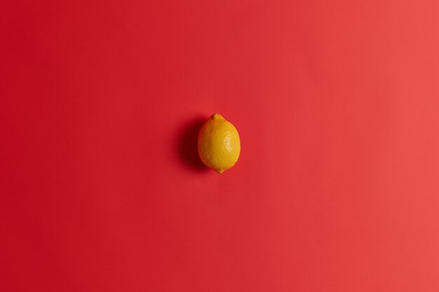 Limão azedo amarelo fresco rico em vitamina C, ácido fólico, fibra e potássio para fortalecer sua imunidade, curar resfriados ou gripes. Suculentas frutas cítricas tropicais suculentas isoladas isoladas em fundo vermelho.