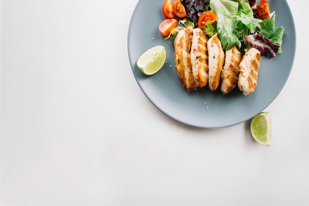 Limão perto de carne assada e salada