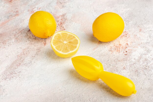 Limões amarelos frescos fatiados e inteiros na superfície branca de vista frontal