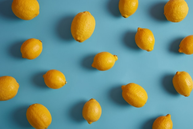 Limões amarelos inteiros cheios de vitaminas e antioxidantes, têm gosto azedo, isolados sobre o fundo azul do estúdio. ingrediente essencial para sua alimentação. peeling útil contendo compostos bioativos