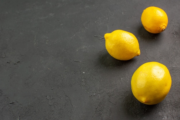 Limões azedos frescos alinhados em uma mesa escura com limão cítrico amarelo