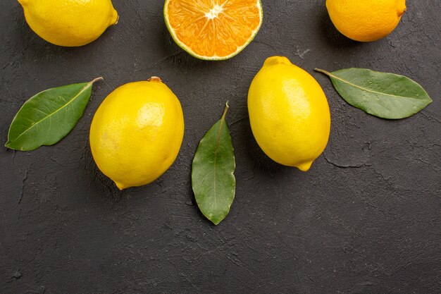 Limões azedos frescos alinhados na mesa escura com frutas cítricas e limão amarelo