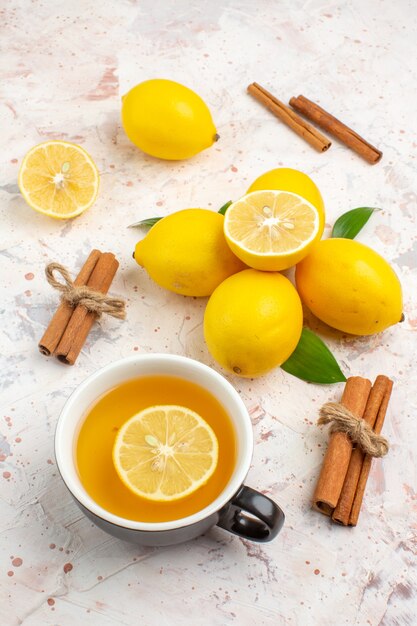 Limões frescos cortados de limão em paus de canela, uma xícara de chá de limão no fundo brilhante isolado.