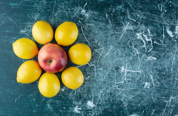 Limões suculentos e maçã vermelha na mesa de mármore.