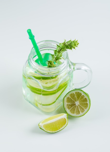 Limonada com limão, palha, ervas em um vidro de frasco de pedreiro em branco, vista de alto ângulo.