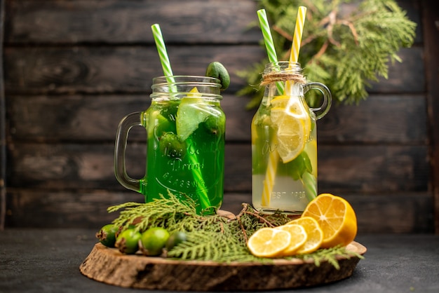 Limonada de frente com feijoa e limão na tábua de madeira corta limões e feijoas na superfície escura isolada